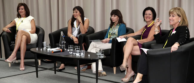 an image of Nancy and three other women sitting on stage speaking to an audience 